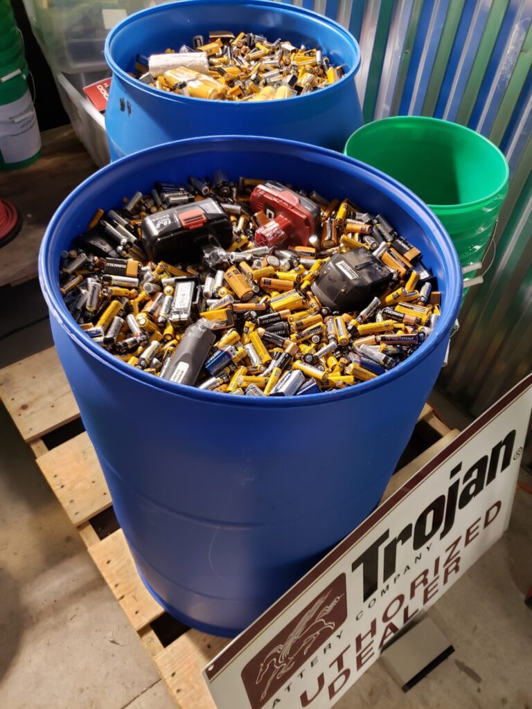 two 55 gallon drums filled with batteries